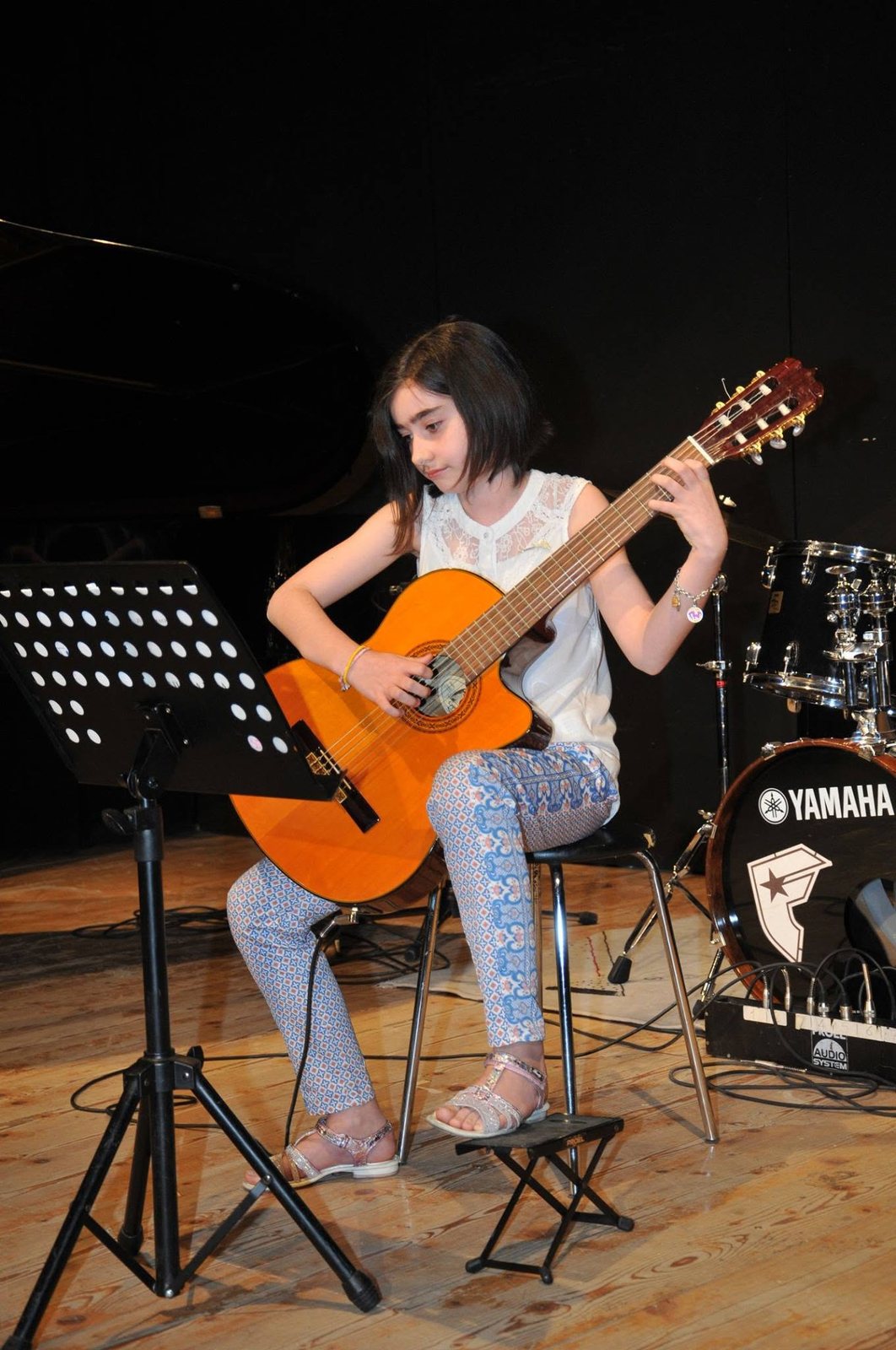Giovane allieva con chitarra classica sul palco